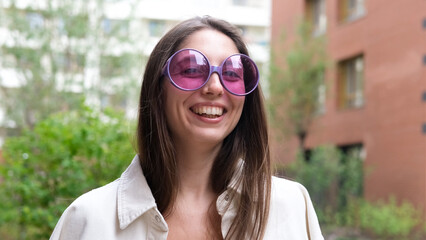Portrait of an attractive woman with a beautiful smile and long hair against the backdrop of a residential area on a summer day.