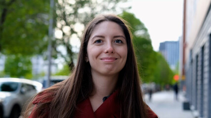 Portrait photo of happy young smiling woman in burgundy coat during city walk outdoors