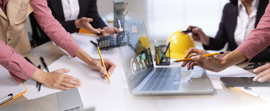 Professional engineers and business colleagues collaborating on project planning using a laptop with advanced digital dashboard interface, data analytics, and global logistics map in a modern office.