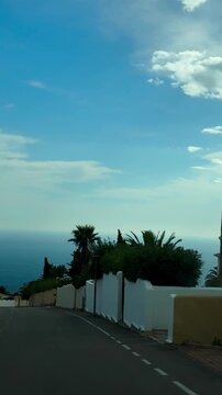 Cumbre del Sol-Encinas, 80, 03726 Benitachell, Alicante, Spain October 20, 2025. Vertical video shot from a car. View from the window of a seascape. Beautiful landscape. palm trees at sunset