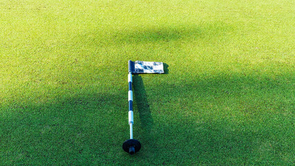 Obraz premium Golf flag on the green in bright sunlight during a daytime round of play
