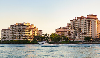 Fototapeta premium Yacht at Fisher island luxury residential building. Vacation on summer. Fisher island building. Luxury motor boat yacht. Yacht go to marina. Boating and yachting. Luxury lifestyle