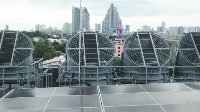 Two engineers in blue uniforms and helmets inspect large rooftop HVAC systems, communicating via radio and discussing maintenance work.