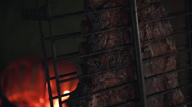 Closeup Argentinian barbecue ribs cooking on outdoor grill, meat on fire details