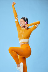 Young woman fitness model in orange athleisure posing mid-stretch with one knee raised, wearing...