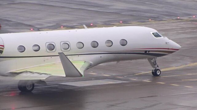 private jet taxiing zurich airport green anti icing fluid coating wing surfaces nose gear follows illuminated taxiway lines wet apron anti-icing executive transport 