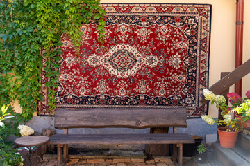 Rustic wooden bench in front of a vibrant red Persian rug