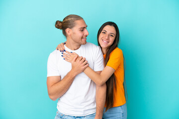 Fototapeta premium Young caucasian couple isolated on blue background laughing and hugging