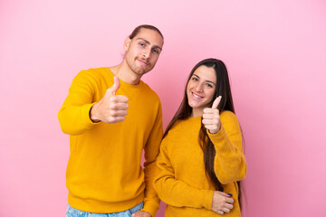 Obraz premium Young caucasian couple isolated on pink background giving a thumbs up gesture because something good has happened