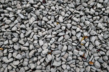 Close-up shot of a textured, monochromatic bed of angular, crushed gray gravel, forming a dense, patterned surface for construction, landscaping, or background use, capturing detail.