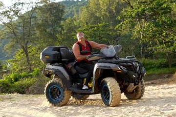 Fototapeta premium A man engages in extreme ATV riding on sand beach early in the morning