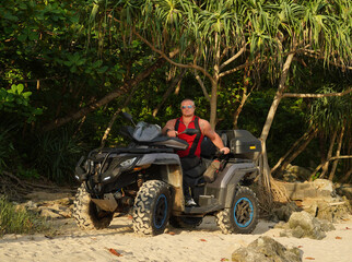 Fototapeta premium A man engages in extreme ATV riding on sand beach early in the morning
