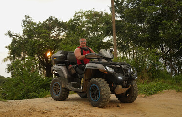 Fototapeta premium A man engages in extreme ATV riding on mountains in the evening