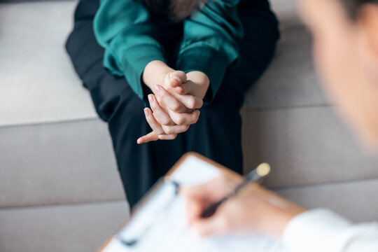 Shot of beautiful woman having therapy while the psychologist takes notes, sitting on the couch in the psychology office