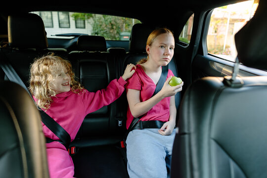 Two sisters with different emotions sitting in car, sibling relationship and family dynamics