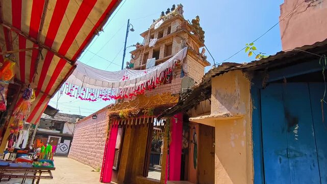 Sri Mahalakshmi Venkateshwara Swamy temple entrance with gopuram and shops at Kodangal, tandur, telangana, india. day time, stable shot, low angle shot, 4k.