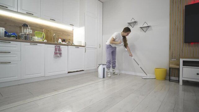 Woman mops the floor in a home interior, capturing household chores, cleanliness, and daily domestic routine, emphasizing hygiene, care, and organized living.