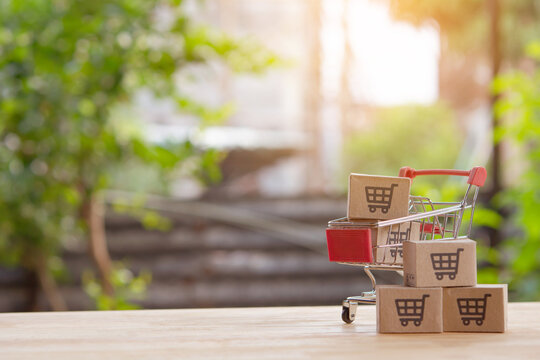 Mini shopping cart with cardboard boxes on wooden table