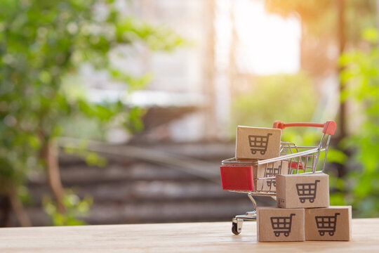 Mini shopping cart with cardboard boxes on wooden table
