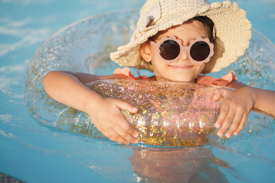 Cute funny toddler girl relaxing on inflatable toy ring floating in pool have fun during summer vacation. Child having fun in swimming pool. 