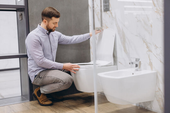 Man selecting new toilet and bidet for home renovation, choosing modern bathroom sanitaryware in a showroom