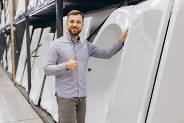 Fototapeta premium Happy man giving thumbs up, choosing a new bathtub for bathroom renovation in a hardware store