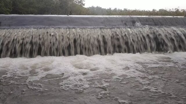 Overflowing lake water flowing over dam spillway in full HD