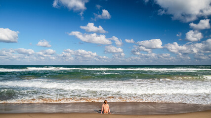 Obraz premium Woman sitting at shoreline watching waves - Black Sea coast in Obzor Bulgaria summer seascape