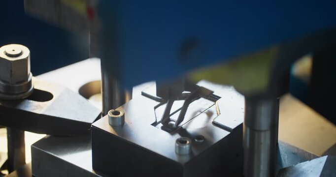 Industrial stamping die shaping metal components on factory floor, focus on heavy machinery and production work