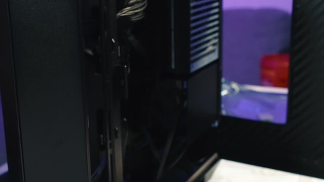 Removing the side panel of a desktop computer case by hand after unscrewing screws to gain access to internal components
