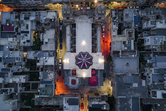 Aerial view of the illuminated Parish Church of Stella Maris standing majestically amidst the urban sprawl, a beacon of light and architectural grandeur, Sliema, Malta.