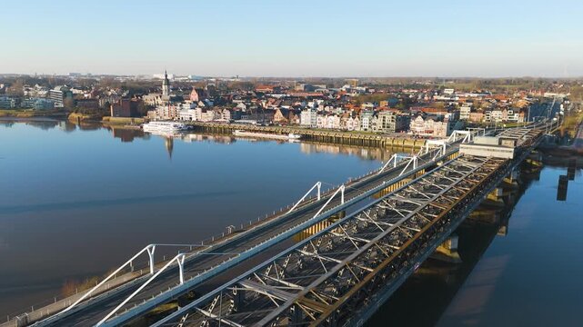 perspective displays parallel road steel railway bridge crossing glassy river dense belgian town skyline colorful houses church towers waterfront toward drone temse belgium buildings 
