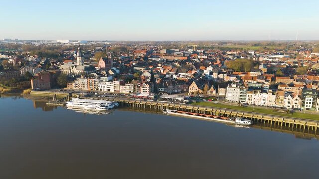 panorama displays calm riverfront lined elegant belgian townhouses church spires moored riverboats compact historic town spreading inland under clear blue sky wide drone temse belgium 