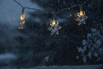 decorative snowflake light string on frosty window