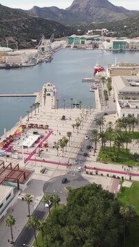 Cartagena touristic port and cityscape with El Zulo sculpture in the background. Vertical aerial.