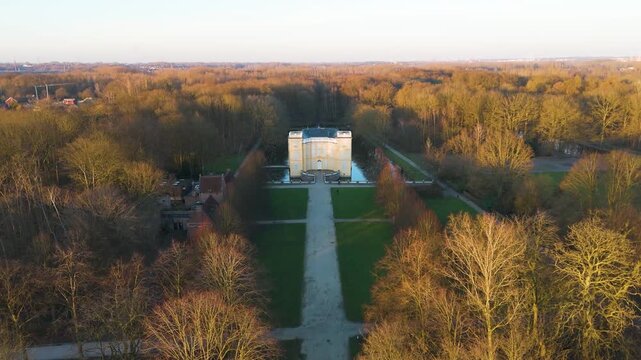 centered golden hour bornem looks gravel path through glowing treetops elegant pale yellow fa&ccedil;ade d&rsquo;ursel castle manicured lawns woodland toward down drone view belgium 