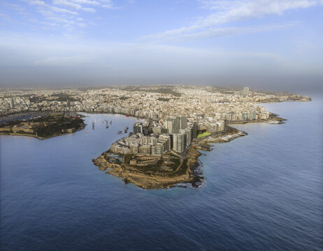 Aerial view of the densely packed buildings of Sliema meet the azure sea, a contrast of urban sprawl and natural beauty, Sliema, Valletta, Malta.