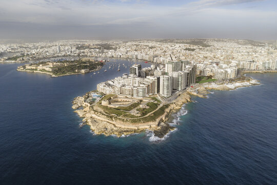 Aerial view of the historic Fort Manoel juxtaposed with the modern skyline, a dramatic contrast of old and new against the deep blue sea, Sliema, Valletta, Malta.