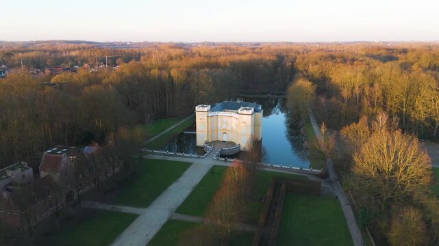 golden hour bornem d&rsquo;ursel castle above pale yellow walls mirrored calm moat straight garden paths glowing woodland soft evening horizon from drone shot belgium stately home 