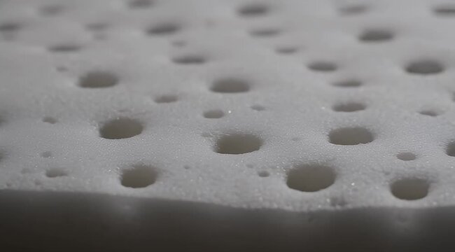 Close up of white foam padding with many rounded holes in it