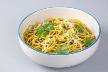 Delicious pasta with pesto sauce, basil and cutlery on white background