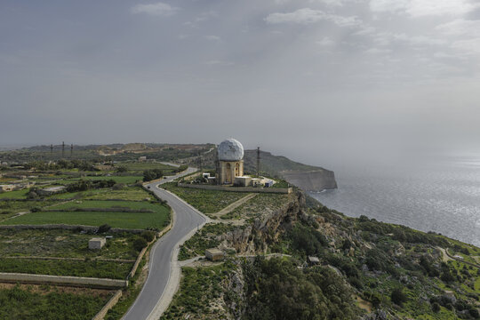 Aerial view of the iconic Meteorological Office radar tower perched atop Dingli Cliffs, where the land meets the sea under a vast sky, Dingli, Dingli, Malta.