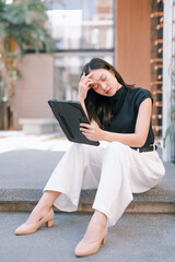 Asian woman experiencing stress and headache using tablet