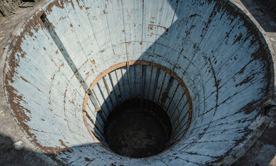 Naklejka premium Turbine shaft ruin circular structure looking into a weathered abandoned pit with peeling paint and dramatic shadows