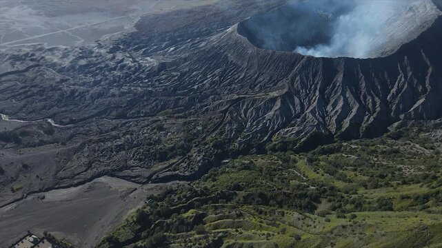 Aerial 4K view of Mount Bromo volcanic crater with active smoke and rugged caldera in East Java.
