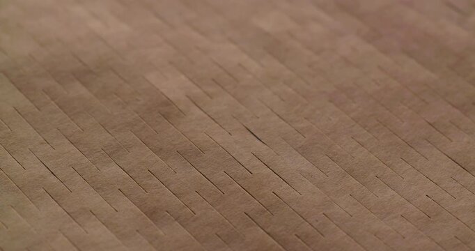 Brown Kraft Cardboard Texture with Diagonal Ridges. Gentle macro panning footage across a warm-toned ridged paper surface, highlighting parallel linear grooves and natural fiber patterns.