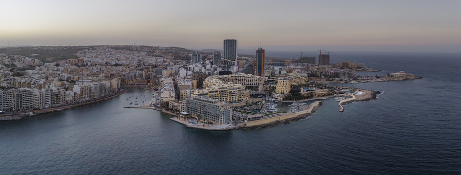 Aerial view of the urban landscape with its modern architecture meeting the tranquil sea, a blend of beige buildings and blue waters, St. Julian's, Sliema, Malta.