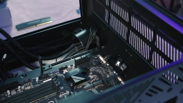 Screwing motherboard to computer case during assembly with screwdriver, close-up view of PC build process
