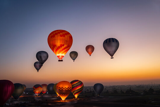 varios globos o balones aerost&aacute;ticos volando por el cielo de Luxor en Egipto al amanecer en la hora azul