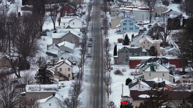 Aerial view of quiet American small town main street after fresh snowfall. Snow covered rooftops and sidewalks line calm road. Peaceful winter atmosphere in rural USA. Loretto, Pa.